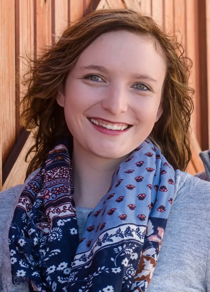 Sarah, smiling in front of a brick wall